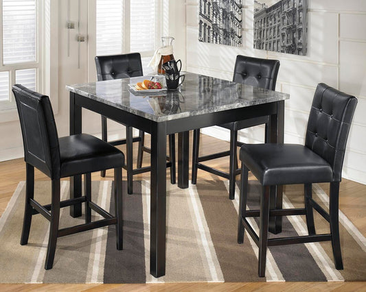 The Maysville Square Counter TBL Set (5/CN), featuring a faux marble tabletop and four black cushioned chairs, sits on a striped rug in a bright room with wall art and large windows.