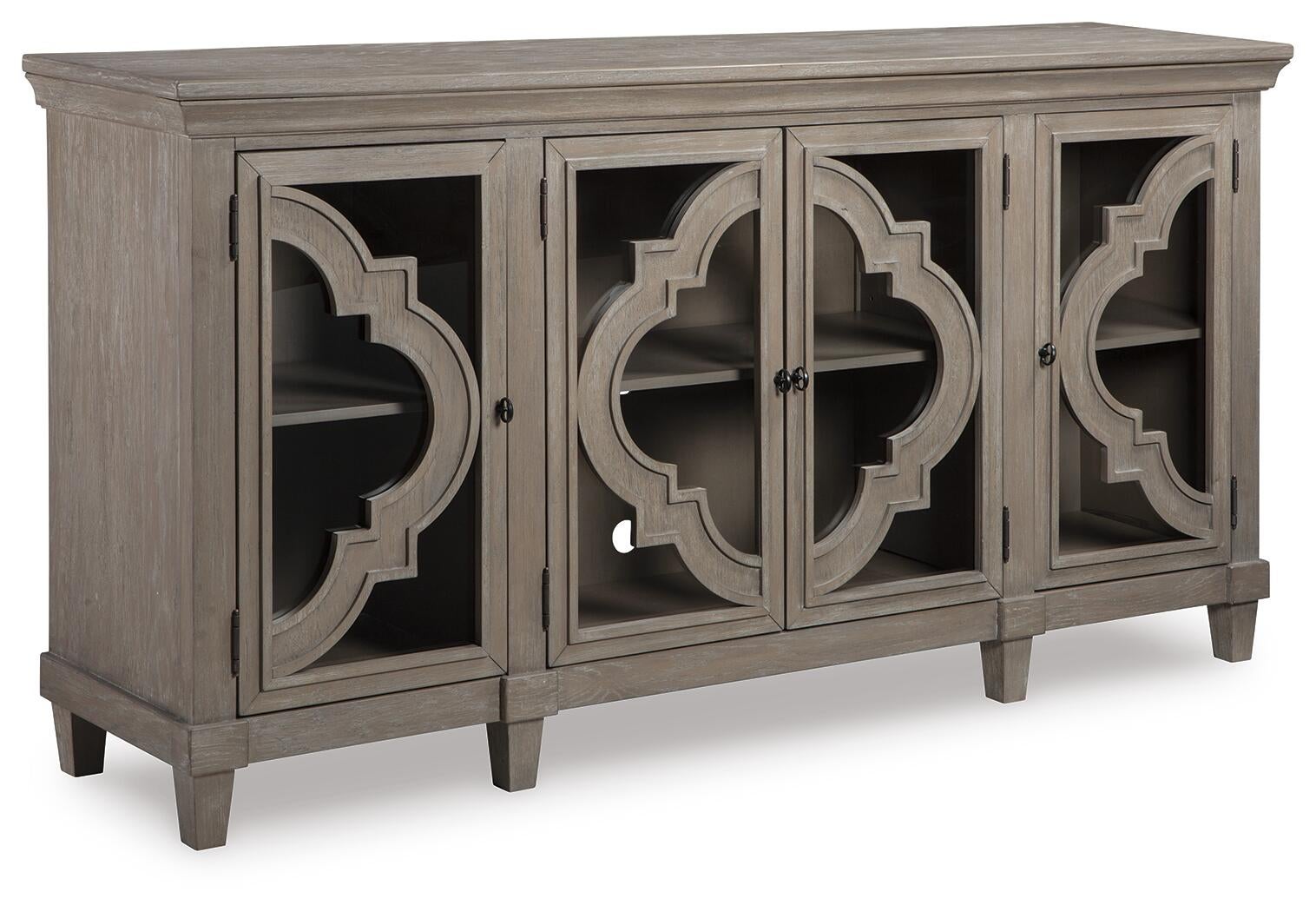 The Fossil Ridge Accent Cabinet is a gray wooden 4-door cabinet with glass inlays, decorative geometric patterns, two adjustable shelves inside, and short legs.