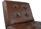 Close-up of the Sidewinder Accent Chair's backrest and seat, showcasing brown faux leather with button-tufted upholstery and visible stitching.