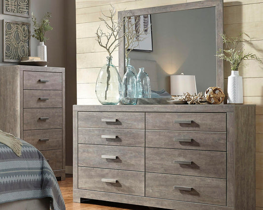 A bedroom showcases the Culverbach Dresser and Mirror in a weathered driftwood finish, six roomy drawers, a matching tall chest, glass vases, a lamp, plants, neutral colors, and geometric decor for a stylish look.