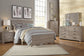 Modern bedroom with light wood furniture, patterned bedding, large window, nightstand, and feather wall art. The Culverbach Dresser and Mirror offer a weathered driftwood finish and six spacious drawers for ample storage.