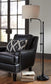 A black leather armchair with silver studs, a patterned cushion, and two open books on the wooden floor sits near tall windows, accompanied by the Anemoon Metal Floor Lamp with a metal base and adjustable arm.