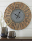 The Payson Wall Clock, featuring a wood and metal design with large Roman numerals, hangs above a table adorned with two ceramic vases and a small branch arrangement.