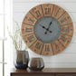 The Payson Wall Clock hangs above a dark wood surface with two glossy ceramic vases holding branches, placed beside a window with white trim.