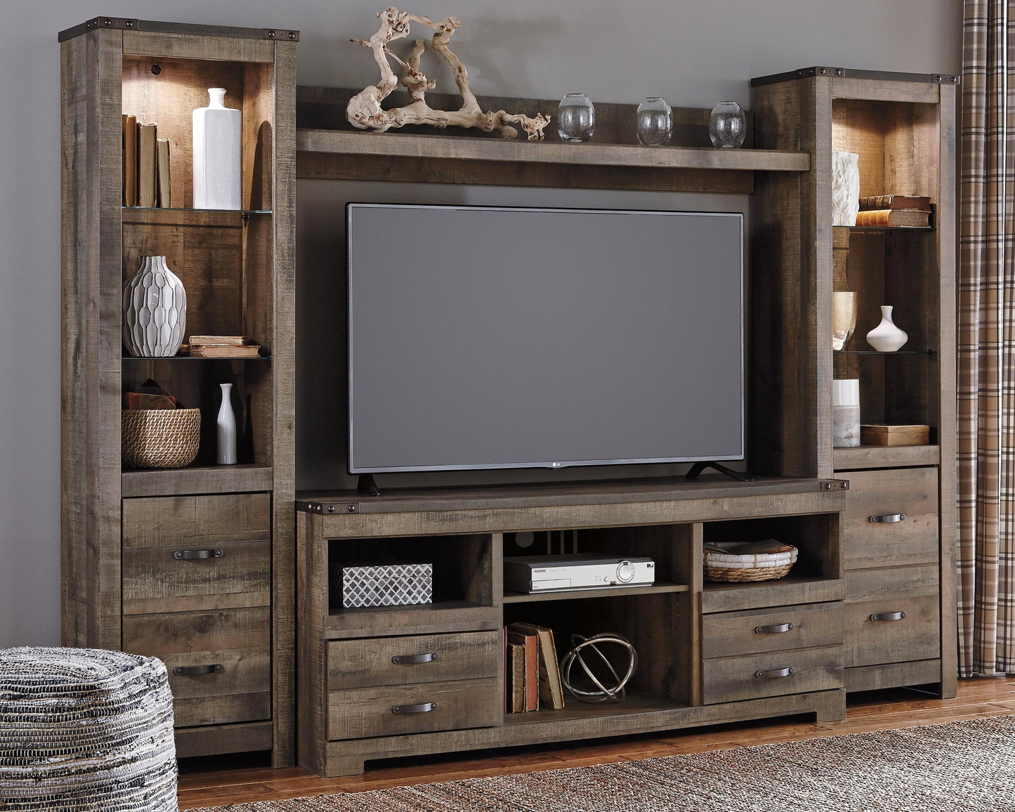The Trinell 4-Piece Entertainment Center features a rustic wood finish, shelves, and cabinets for displaying decor, with space for a flat-screen TV in the center.