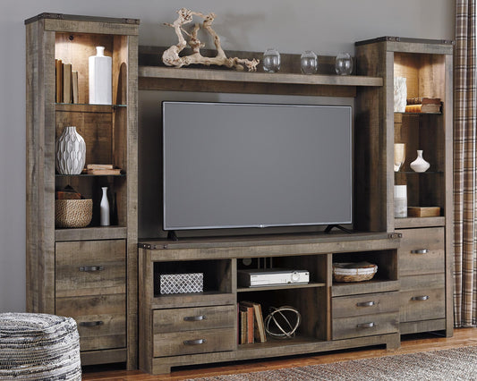The Trinell 4-Piece Entertainment Center features a rustic wood finish, shelves and drawers for a flat-screen TV, décor, baskets, and books, perfect for display against a gray wall.